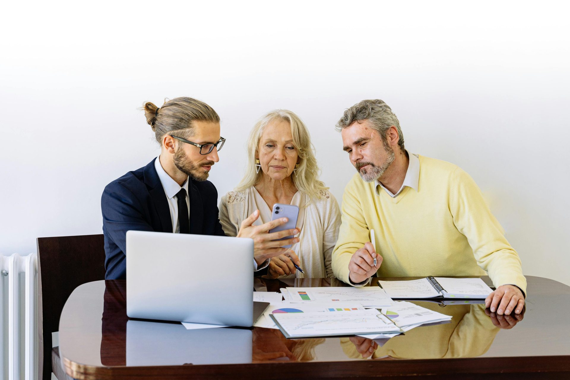 Advisor showing phone to older couple attentively.