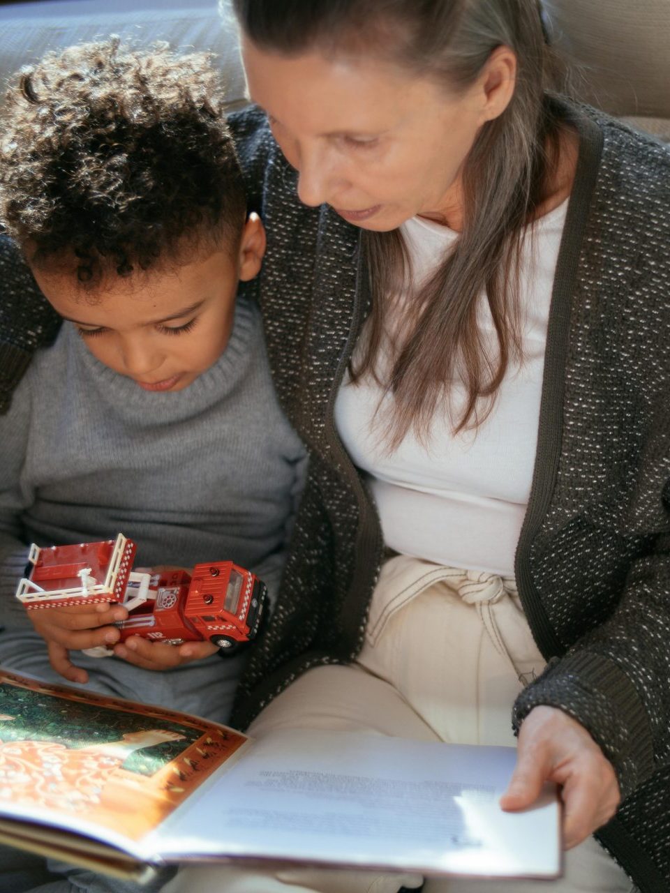 Grandmother reading book with grandson cuddling.
