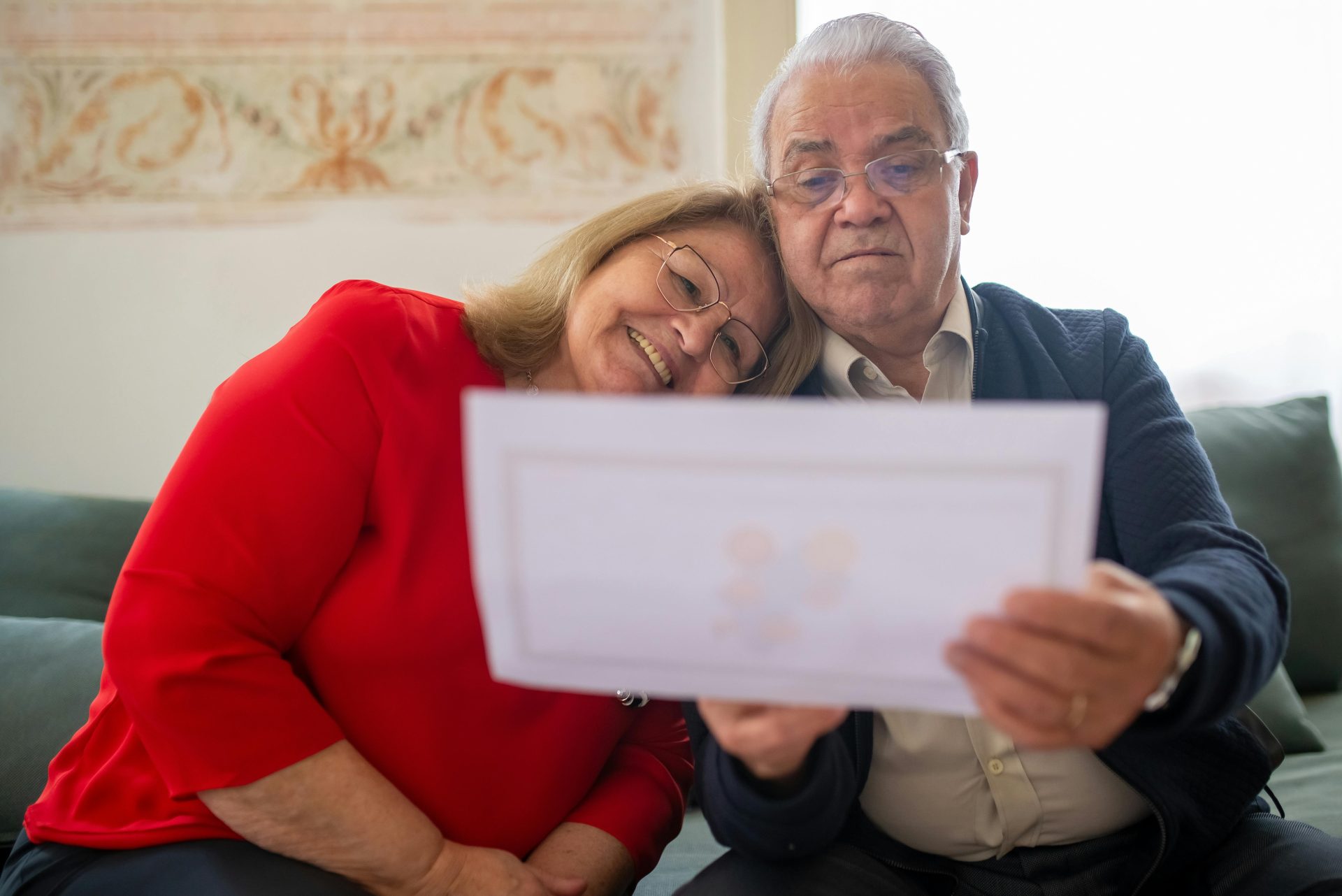 Elderly couple smiling, looking at photo together.