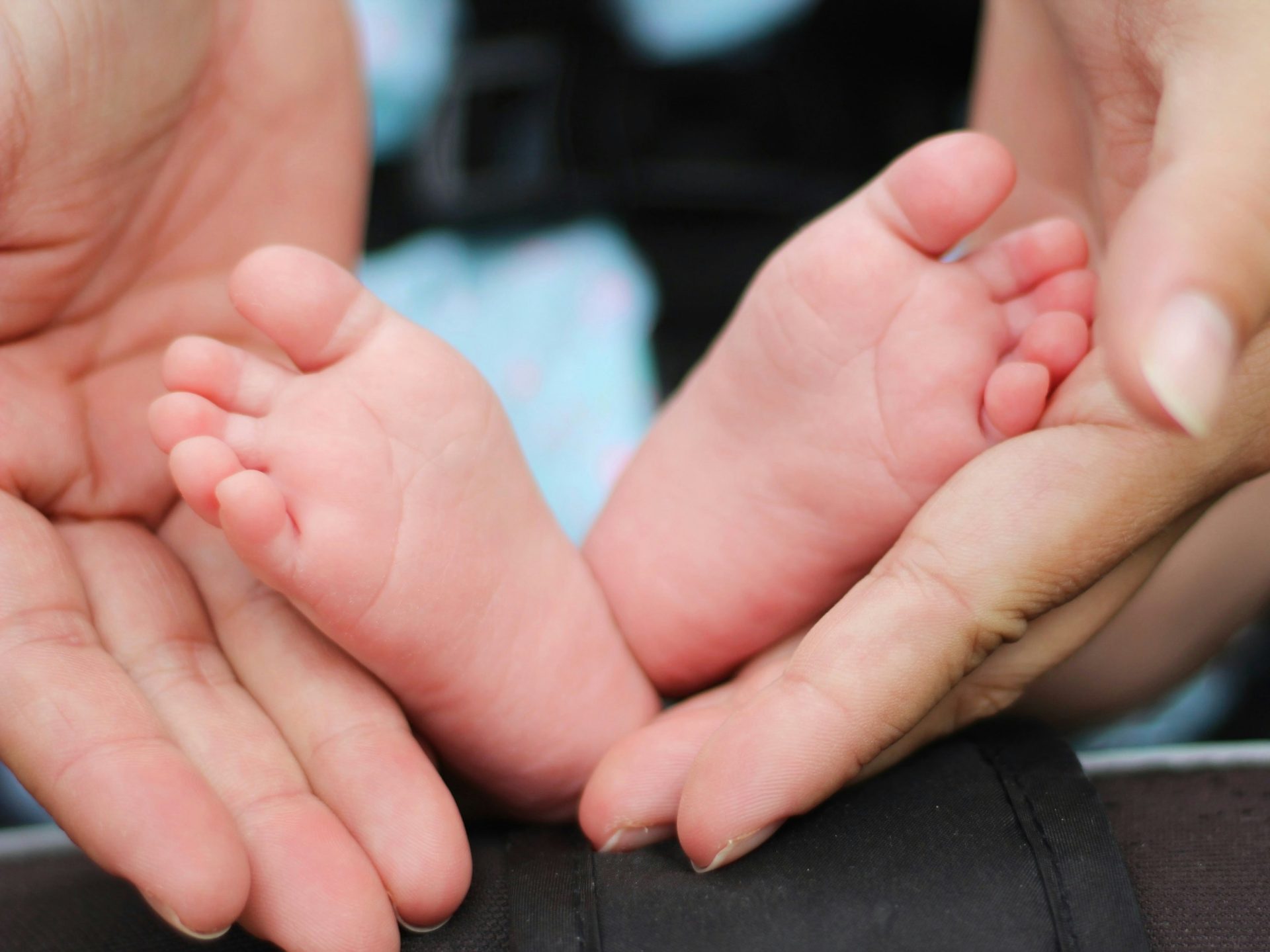 Tiny baby feet held in hands.